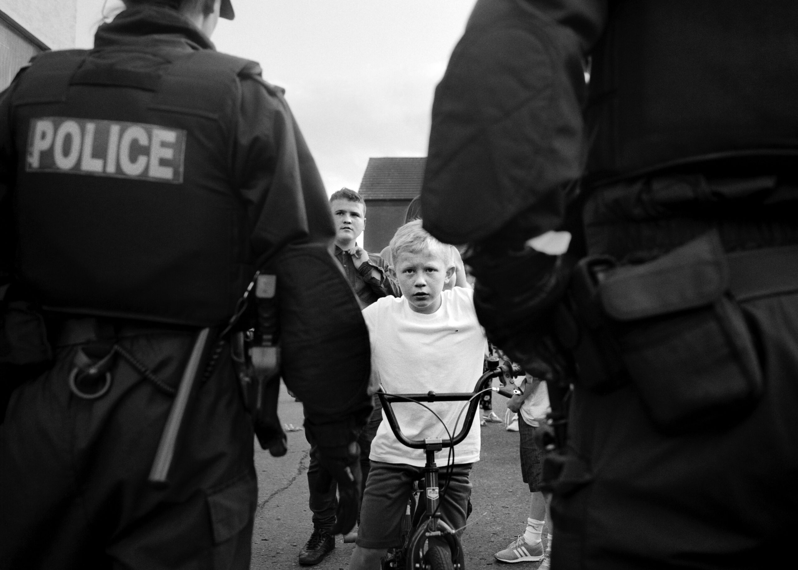 Brendan behind a police line on Trinity Street, from the series 'Wee Muckers'